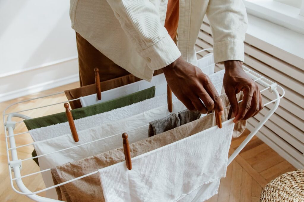 A close-up of a person hanging laundry on an indoor drying rack, highlighting domestic life.