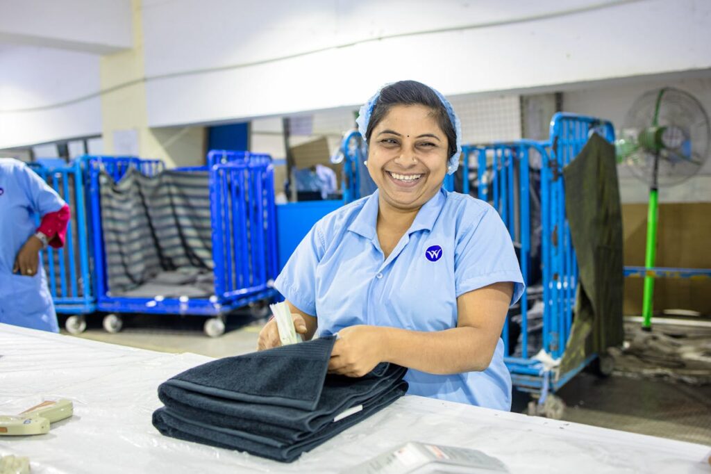 Cheerful factory worker folding textiles in an industrial setting.