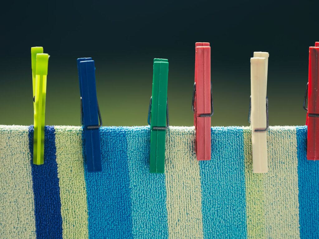 Brightly colored clothespins secured on a striped towel in the sun, perfect for lifestyle themes.